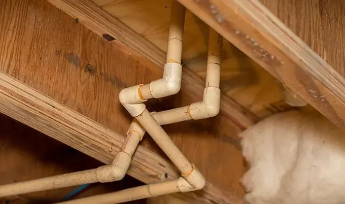 Exposed supply pipes in floor joists that froze and split during a Long Island winter